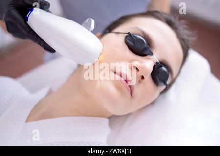 Porträt einer entspannten jungen Klientin, die eine SMAS Ultraschall-Gesichtsliftmassage mit professioneller Ausstattung im Beauty Center erhält Stockfoto