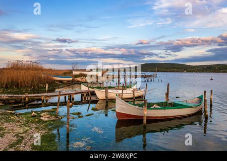 Der ruhige Nachmittag auf einem See mit einem hölzernen Pier und Booten am farbenfrohen Himmel. Stockfoto