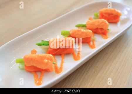 Japanisches Fusionsküche Lachs mit Mentaiko-Quelle, serviert auf weißem Teller. Stockfoto