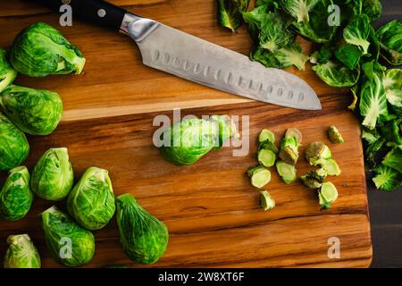 Geschnittene Rosenkohl auf einem Holzschneidebrett: Geschälte und zugeschnittene Babykohl mit Blättern und Stielen auf einem Holzschneidebrett Stockfoto