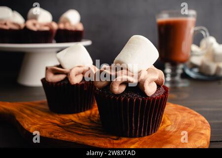 Cupcakes mit heißem Kakaogeschmack und Riesenmarshmallows: Schokoladen-Cupcakes mit Zuckerguss mit heißem Schokoladengeschmack und Marshmallow-Beilage Stockfoto