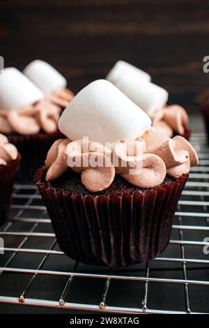 Cupcakes mit heißem Kakaogeschmack und Riesenmarshmallows: Schokoladen-Cupcakes mit Zuckerguss mit heißem Schokoladengeschmack und Marshmallow-Beilage Stockfoto
