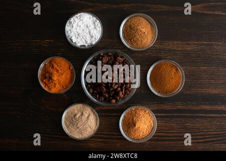 Zutaten für gewürzten Weihnachtskaffee in kleinen Glasschalen: Kaffeebohnen mit Puderzucker, Zimt, Kardamom und gemahlenen Gewürzen auf einem Holztisch Stockfoto