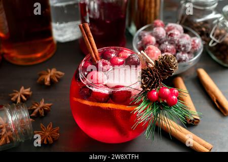 Würziger Cranberry Bourbon Old Fashioned mit gezuckerten Cranberries: Roter Bourbon-Cocktail im Weihnachtsstil garniert mit einem immergrünen Mini-Zweig Stockfoto