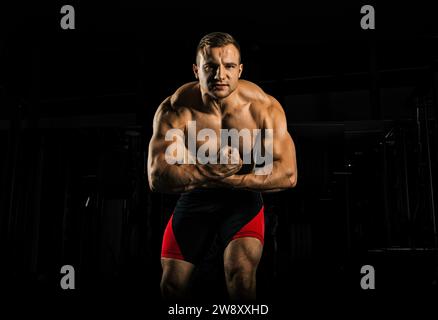 Der Gewichtheber posiert vor der Kamera, spannt seine Arme monströs, während er aus der Spannung schreit. Vorderansicht Stockfoto