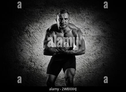 Der Gewichtheber posiert vor der Kamera, spannt seine Arme monströs, während er aus der Spannung schreit. Vorderansicht Stockfoto
