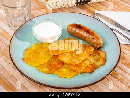 Kartoffelpfannkuchen mit Wurst und Sauerrahm Stockfoto