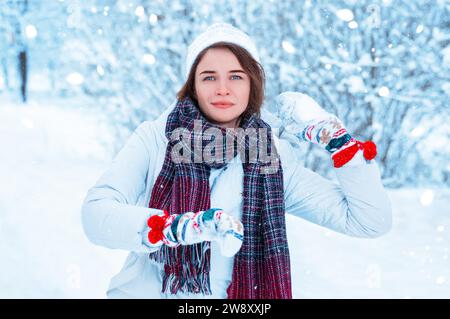 Porträt eines schönen Mädchens, das einen Schneeball wirft. Konzept für Weihnachtsferien, Winterspiele, Glück und Spaß. Gemischte Medien Stockfoto