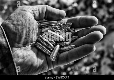 Der Kämpfer hält eine Handvoll Kugeln in seiner Hand für Waffen. Gemischte Medien Stockfoto