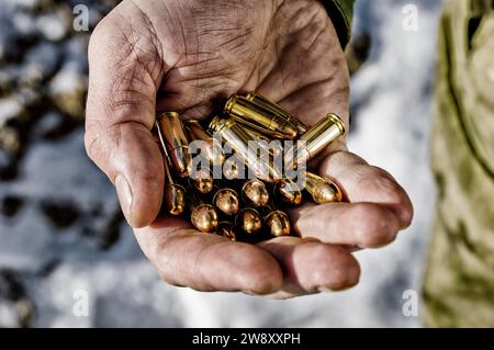 Der Kämpfer hält eine Handvoll Kugeln in seiner Hand für Waffen. Gemischte Medien Stockfoto