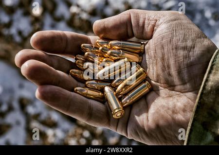 Der Kämpfer hält eine Handvoll Kugeln in seiner Hand für Waffen. Gemischte Medien Stockfoto