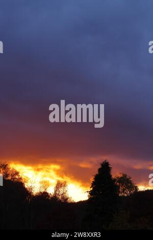 Sonnenuntergang mit dramitischen dunklen Wolken, Sonne scheint durch eine Lücke in den Wolken, roter Himmel, brennender Himmel, Silhouette, Rothaargebirge, Nordrhein-Westfalen Stockfoto