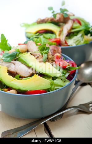Frischer und gesunder Hühnchen Avocado Salat auf rustikalem Holztisch, Lebensmittelfotografie Stockfoto
