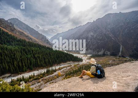 Blick auf das Ala Archa Tal vom Aussichtspunkt, Wanderer auf einem großen Felsen, Broken Heart Rock, herbstliche Berglandschaft, Ak Say und Ala Archa Berg Stockfoto