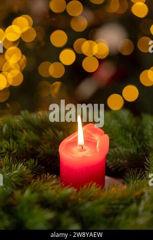 Dekorierter Adventskranz aus Tannenzweigen mit roter brennender Kerze auf einer hölzernen Fensterbank in der Zeit vor Weihnachten Stockfoto