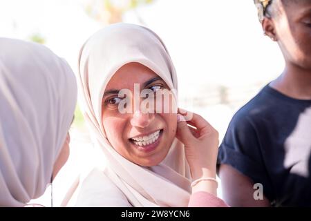 muslimische Frau passt ihren Hijab mit Hilfe einer anderen Person an Stockfoto