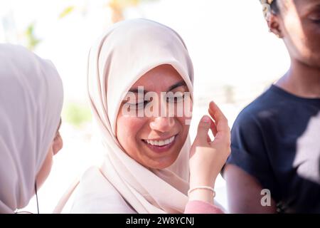 muslimische Frau passt ihren Hijab mit Hilfe einer anderen Person an Stockfoto