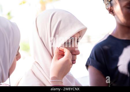 muslimische Frau passt ihren Hijab mit Hilfe einer anderen Person an Stockfoto