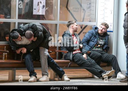 Birmingham 22. Dezember 2023 - Friends Tussle auf der Broad Street in Birmingham am Black Eye Friday - Revellers gingen am Mad Friday nach Birmingham, was auch Black Eye Friday heißt. Die Arbeitsfeiern waren in vollem Gange, als die Geschäfte zu Weihnachten geschlossen wurden. Man sah viele Leute, die durch das Stadtzentrum gingen und ein riesiges Glas Bier auf dem deutschen Markt hielten und viele trugen Weihnachtsmütze. Eine Gruppe von 3 Arbeitskollegen ging in ein mexikanisches Restaurant, und zwei trugen mexikanische Outfits, während ihr Kollege einen traditionellen Weihnachtsmann-Hut trug. Freunde wurden auch auf der Broad Street gesehen, die einen Tussl hatten Stockfoto