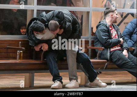 Birmingham 22. Dezember 2023 - Friends Tussle auf der Broad Street in Birmingham am Black Eye Friday - Revellers gingen am Mad Friday nach Birmingham, was auch Black Eye Friday heißt. Die Arbeitsfeiern waren in vollem Gange, als die Geschäfte zu Weihnachten geschlossen wurden. Man sah viele Leute, die durch das Stadtzentrum gingen und ein riesiges Glas Bier auf dem deutschen Markt hielten und viele trugen Weihnachtsmütze. Eine Gruppe von 3 Arbeitskollegen ging in ein mexikanisches Restaurant, und zwei trugen mexikanische Outfits, während ihr Kollege einen traditionellen Weihnachtsmann-Hut trug. Freunde wurden auch auf der Broad Street gesehen, die einen Tussl hatten Stockfoto