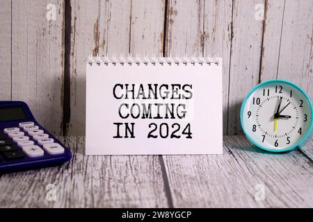 Weißer Notizblock mit TEXTÄNDERUNGEN AB 2024 und Bürowerkzeugen auf blauem Hintergrund Stockfoto