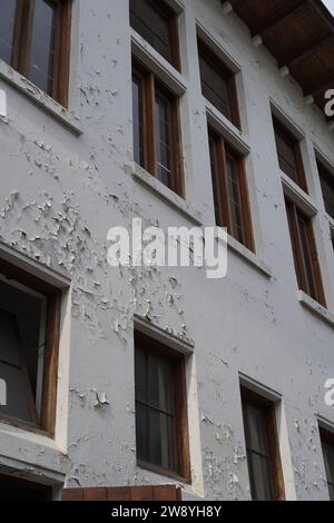Aus den Fenstern des Gebäudes sieht es abgenutzt aus, mit abblätternder Wandfarbe Stockfoto