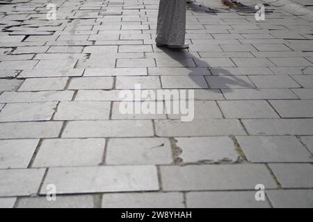 Nahaufnahme von Fußgängerschatten auf der Backsteinstraße Stockfoto