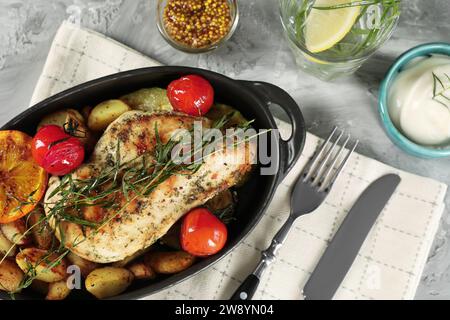 Leckeres Huhn, Gemüse, Getränk mit Estragon und Salatdressings auf grauem Tisch, flache Lay Stockfoto