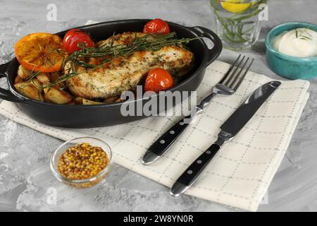 Leckeres Huhn, Gemüse, Getränk mit Estragon und Salatdressings auf grauem Tisch Stockfoto