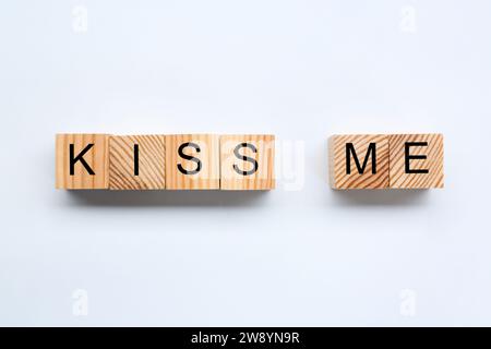 Holzwürfel mit Phrase Kiss mich auf weißem Hintergrund, flach Stockfoto