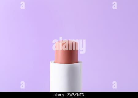 Ein Lippenbalsam auf lilafarbenem Hintergrund, Nahaufnahme. Kosmetisches Mittel Stockfoto