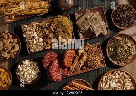 Blick von oben auf traditionelle Medikamente auf Holztabletts, dekoriert auf schwarzer Bambusmatte auf hölzernem Tischhintergrund. Kostbare traditionelle Medikamente werden ausgestellt Stockfoto