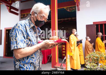 Bandung, Indonesien - 8. Januar 2022 : buddhistische Menschen beten zusammen mit den Mönchen, während sie die Opfergabe vor dem Altar im Inneren des Buddha geben Stockfoto