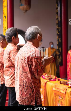 Bandung, Indonesien - 8. Januar 2022: Der alte Mann bringt die Opfer auf den Altar, während er mit den Mönchen im Buddha-Tempel betet Stockfoto