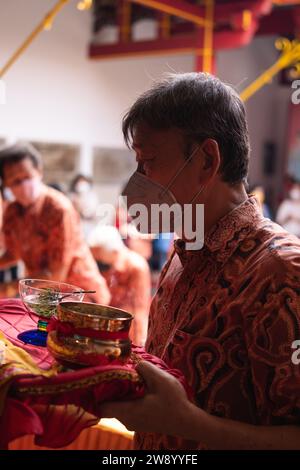 Bandung, Indonesien - 8. Januar 2022: Der alte Mann bringt die Opfer auf den Altar, während er mit den Mönchen im Buddha-Tempel betet Stockfoto