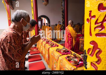 Bandung, Indonesien - 8. Januar 2022: Der alte Mann bringt die Opfer auf den Altar, während er mit den Mönchen im Buddha-Tempel betet Stockfoto