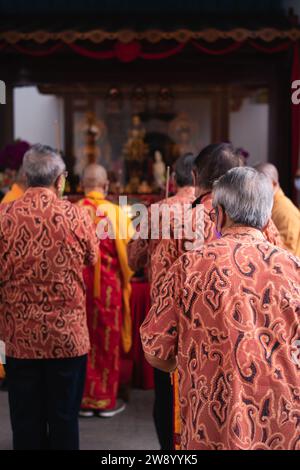 Bandung, Indonesien - 8. Januar 2022: Der alte Mann bringt die Opfer auf den Altar, während er mit den Mönchen im Buddha-Tempel betet Stockfoto