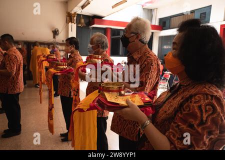 Bandung, Indonesien - 8. Januar 2022: Der alte Mann bringt die Opfer auf den Altar, während er mit den Mönchen im Buddha-Tempel betet Stockfoto