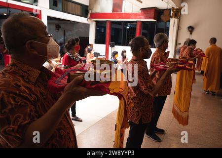 Bandung, Indonesien - 8. Januar 2022: Der alte Mann bringt die Opfer auf den Altar, während er mit den Mönchen im Buddha-Tempel betet Stockfoto