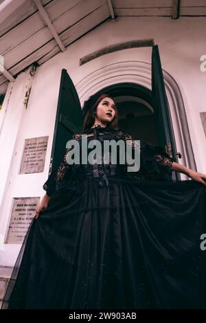 Eine Hexe in schwarzem Kleid geht die Stufen eines Friedhofs hinunter, nachdem sie ihren verstorbenen Bruder am Morgen besucht hat Stockfoto