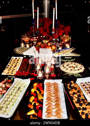 Weihnachtsfeiertage mit Hors d'oeuvre-Auswahl und Dekoration auf dem Tisch mit Kerzen und Rosenblättern. Stockfoto