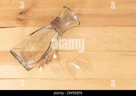 Transparente Glasvase, die auf einem Holztisch zerschlagen wurde Stockfoto