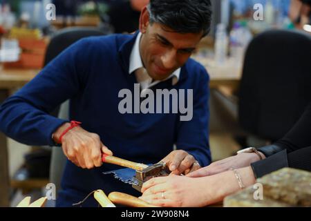 Aktenfoto vom 23. Mai 11/23 von Premierminister Rishi Sunak neben Emma White, der während eines Treffens mit Kleinunternehmern von Sunny Bank Mills im Emma White Jewellery Studio in Sunny Bank Mills, Farsley, West Yorkshire, ein Schmuckstück hämmert. Ausgabedatum: Samstag, 23. Dezember 2023. Stockfoto