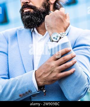 Der Mann hält seine Uhr. Portrait erfolgreicher Geschäftsmann in einem Business-Anzug mit der Uhr. Geschäftsmann zeigt auf seine Uhr Stockfoto