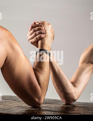 Arme ringen dünne Hand, großer starker Arm im Studio. Zwei Männerhände umklammten Arm Wrestling, stark und schwach, ungleiche Übereinstimmung Stockfoto