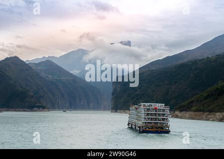Ein einsames Boot durchquert das ruhige Wasser des Yangtse-Flusses, inmitten der nebeligen Berge des Fengjie County, China, das am 17. März 2018 eingenommen wurde. Stockfoto