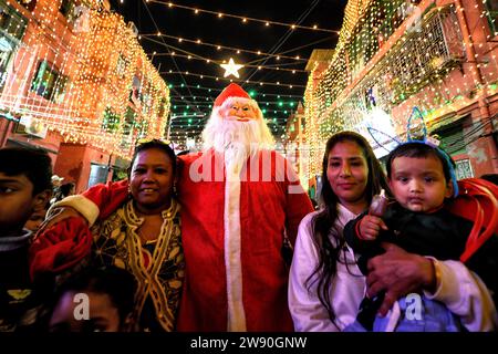 Kalkutta, Indien. Dezember 2023. Ein Mann, der als Weihnachtsmann gekleidet ist, posiert für Fotos mit Frauen und Kindern während einer Weihnachtsfeier in Kalkutta. Quelle: SOPA Images Limited/Alamy Live News Stockfoto