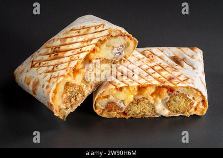 Französische Tacos mit Falafel. Schneiden Sie französische Tacos aus nächster Nähe auf schwarzem Hintergrund. Köstliches französisches Taco-Sandwich Fastfood, gutes, tolles Essen Stockfoto