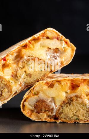 Französische Tacos mit Falafel. Schneiden Sie französische Tacos aus nächster Nähe auf schwarzem Hintergrund. Köstliches französisches Taco-Sandwich Fastfood, gutes, tolles Essen Stockfoto