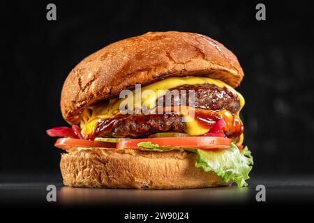 Köstlicher Doppelkäseeburger mit amerikanischem Käse, Salat, Tomaten, roten Zwiebeln, Gurken, und Farmhaus-Brötchen aus der Nähe auf schwarzem Hintergrund. Köstlich c Stockfoto